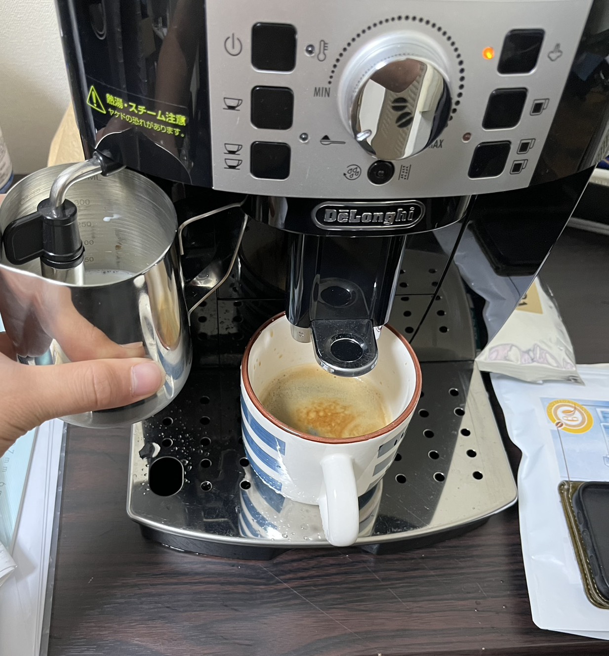 マグニフィカSの手動フロッサーでピッチャー内の牛乳を泡立てている様子